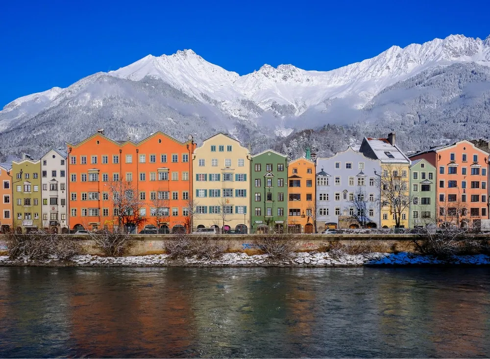 Bunte Häuser vor Berglandschaft in Innsbruck auf dem Kurztrip nach Österreich