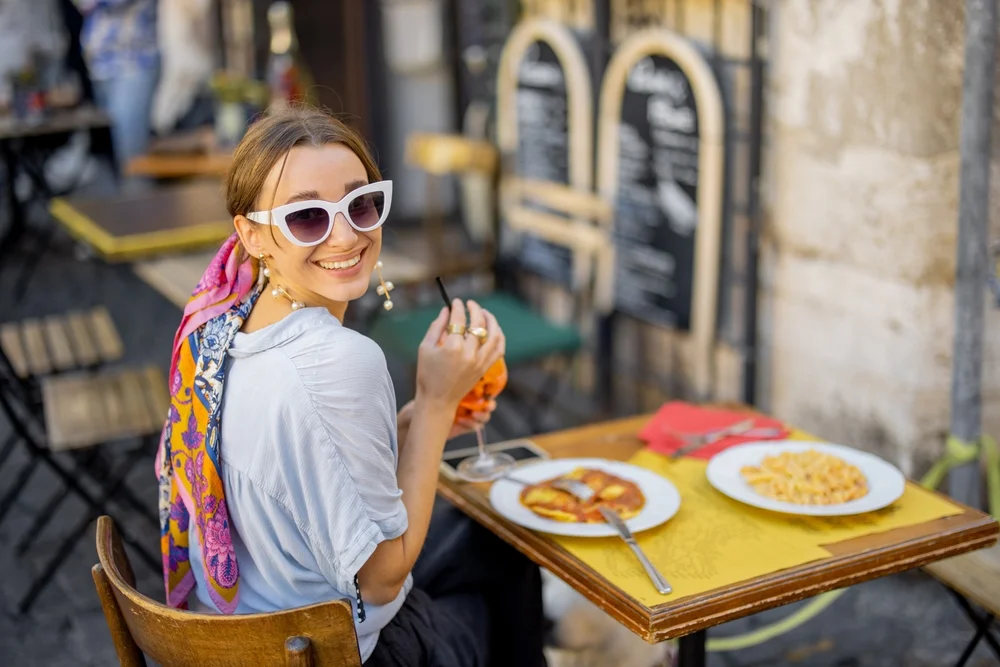 Junge Frau genießt traditionelle italienische Küche in einer engen Gasse auf ihrer Städtereise nach Rom