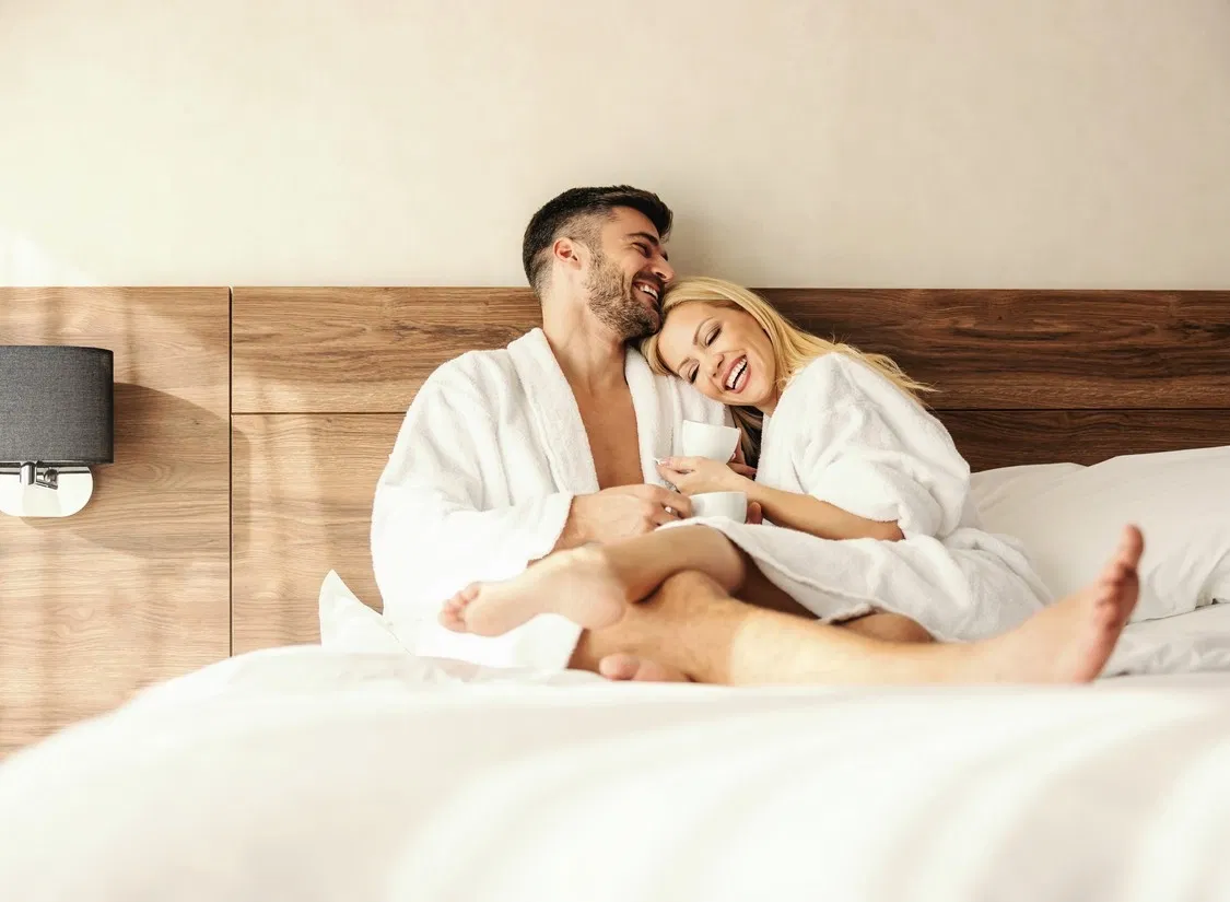 Im Thermenhotel liegt ein Paar mit Bademänteln im Bett